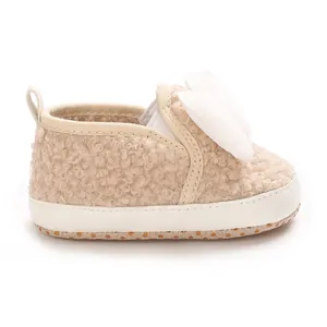 Close-up of baby girl fleece crib shoe with large white decorative pom-pom bow
