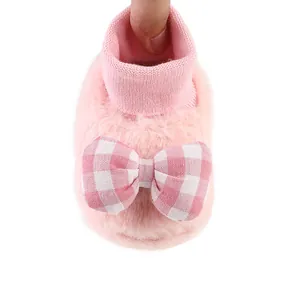 Detailed view of soft pink fuzzy baby booties featuring a cute checkered bow design