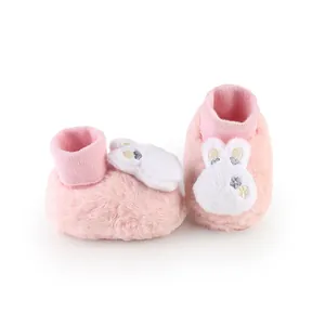 Detail of soft pink plush baby shoes with cute white rabbit embroidery for winter.