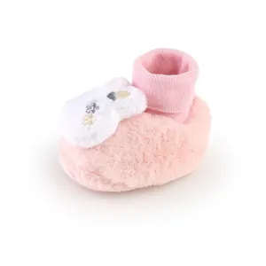 Detailed macro view of soft pink plush baby bootie featuring embroidered flower patch