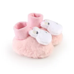 Close-up of soft pink plush baby booties with white rabbit plush decoration for winter