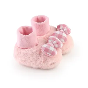 Detailed view of soft pink plush baby walker shoes with a checkered bow ornament.