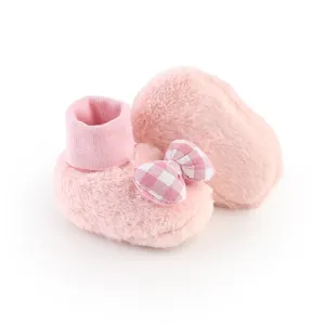 Detailed close-up of soft plush pink baby booties with a cute checkered bow decoration.