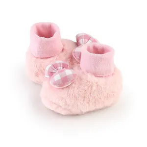 Close-up of pink fluffy baby booties with checkered bow detail for newborn toddlers