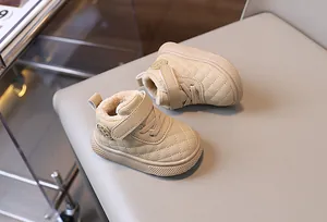 Primer plano de botas de invierno para bebé acolchadas en beige con forro de piel sintética.