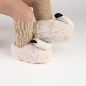 Close-up of fluffy cream baby slippers with cute ear details and warm socks