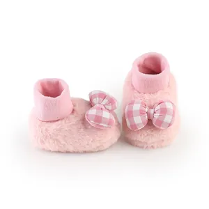 Detail shot of pink plush winter baby floor shoes with cute checkered bow decor