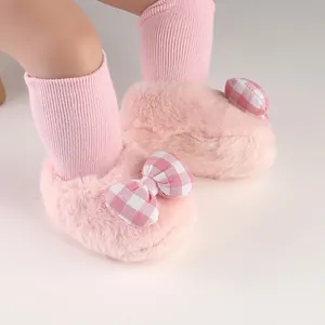 Macro view of pink fuzzy baby slippers with a cute checkered bow and ribbed sock details