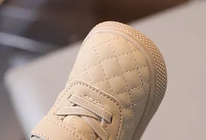 Primer plano de zapato beige acolchado para niños con detalles de costuras y cordones elásticos