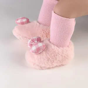 Detail view of soft pink fuzzy baby shoes featuring a cute checkered bow for winter season