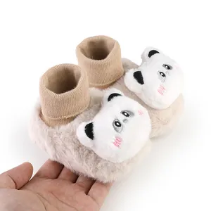Detailed macro view of plush baby winter booties with cute panda design held by hand