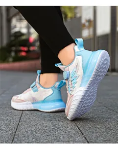 Zapatillas deportivas de niña con alas brillantes sobre pavimento