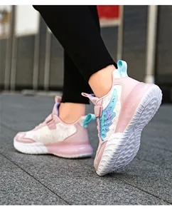 Detalle de zapatillas rosas para niñas con diseño de alas brillantes en pavimento.