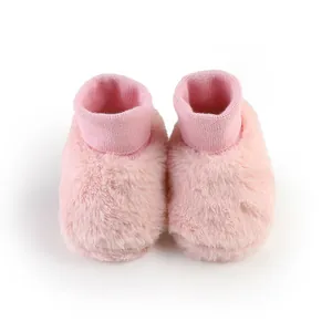 Gedetailleerde weergave van roze pluizige babyschoentjes met warme gebreide sokboord