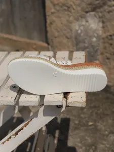 Detailed view of women's wedge sandal showing white platform sole with rope texture