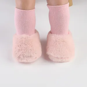 Close-up van roze pluizige baby-loopschoenen met geïntegreerde gebreide sokken voor de winter