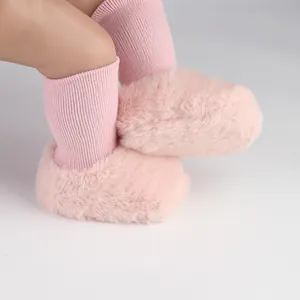 Detailopname van roze imitatiebont baby pre-walker schoenen met gebreide sokken.