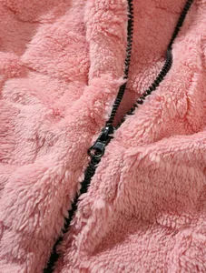 Macro close-up of a pink fluffy fleece jacket with black zipper detailing for winter.