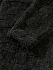 Macro detail of black thickened fleece hoodie with embossed checkered texture fabric
