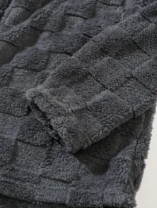 Detailed close-up of grey fleece fabric with embossed grid pattern on a winter jacket