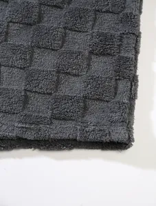 High-quality close-up of dark grey plush checkered fabric texture for winter hoodie
