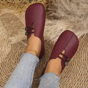 Burgundy soft leather slip-on loafers with decorative button detail worn on woven mat