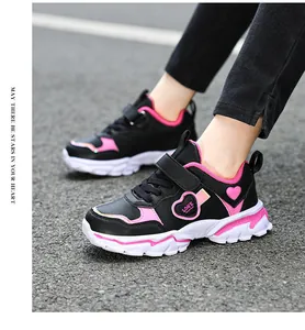 Close-up of girl's black and pink heart sneakers on an asphalt background