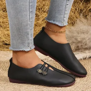 Close-up detail of black soft leather women's casual slip-on flats with metallic buttons
