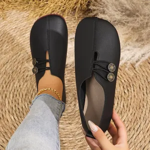 Detailed view of women's black soft leather slip-on flats with decorative buttons