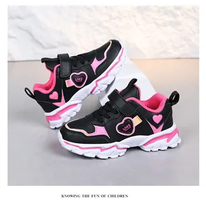 Close-up of girls pink and black sports shoes with heart patterns and Velcro strap.