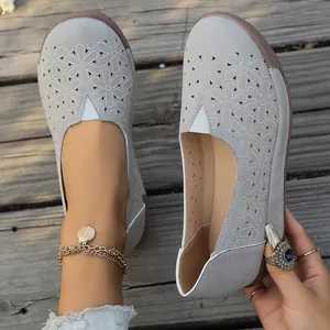 Primer plano de zapatos planos grises estilo étnico con detalles florales calados y diseño slip-on