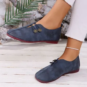 Detailed view of women's navy blue soft leather loafers featuring decorative buttons and red sole