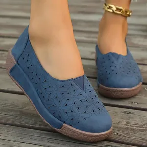 Primer plano de zapatos planos azules con elegantes motivos florali calados a láser.