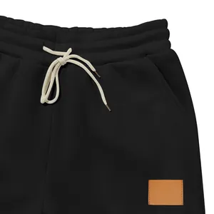 Vista detallada de los pantalones de chándal negros para hombre con cordón y parche de cuero