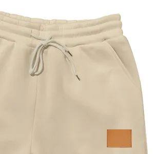 Detalle de pantalones de chándal crema con cintura elástica y cordón de ajuste a juego