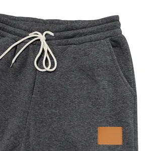 Detalle de pantalones deportivos gris marengo para hombre con cordón y parche
