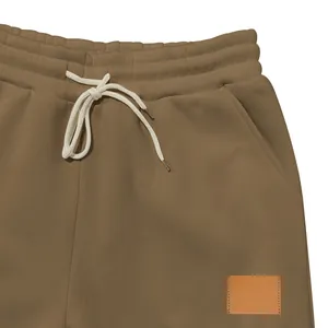 Detalle de cerca de pantalones de chándal marrones para hombre con cordón blanco.