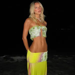 Model trägt ein sexy Neckholder-Top aus Mesh und ein Set mit geschlitztem Rock am Strand