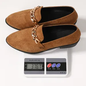 Gedetailleerde gewichtsmeting van bruine puntige damesloafers met gouden ketting