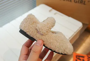 Nahaufnahme beiger Lammwoll-Kinderschuh mit Riemen und schwarzer Gummisohle für Winter