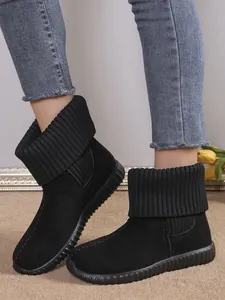 Close-up of black winter snow boots with a thick knitted collar and decorative stitching