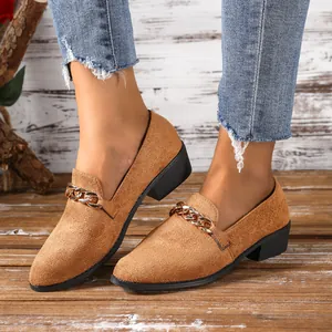 Detailopname van bruine suède puntige loafers met gouden ketting aan de voeten