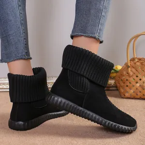 Close-up of black suede snow boots with ribbed knit collar and flat non-slip sole