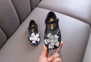 Detail of sparkly black girls' Mary Jane shoes with a large rhinestone flower for parties