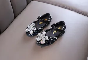 Detail view of sparkly rhinestone flower decoration on black girls princess shoes