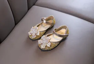 Detail of golden sequined girls' princess shoes with rhinestone flower ornament