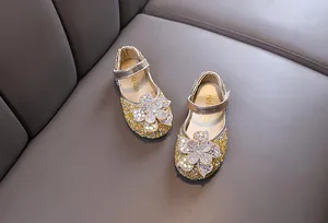Detailed view of girls golden princess shoes featuring sparkly rhinestones and flower decoration