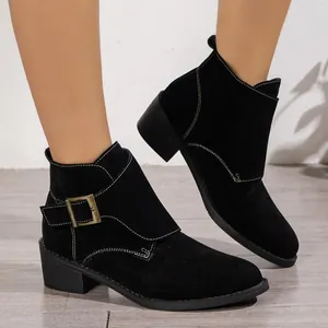 Gros plan de bottines en daim noir avec boucle en bronze vintage et surpiqûres blanches