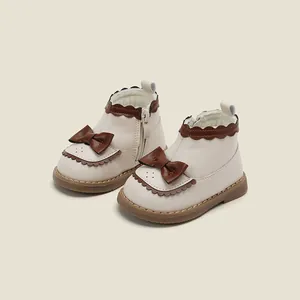 Elegante cremefarbene Kleinkind-Prinzessinnenstiefel mit brauner Schleife und Wellenrand