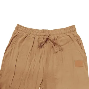Dettaglio di pantaloni in cotone e lino da uomo con coulisse color marrone.